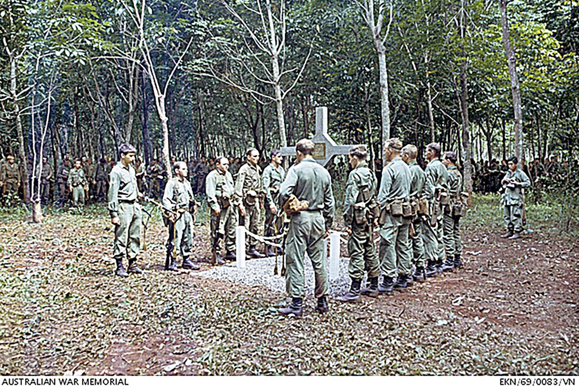 Veterans of the Battle of Long Tan line either side of the Long Tan Cross at a memorial service on August 18 1969, while the remainder of the battalion assemble nearby in the trees.
