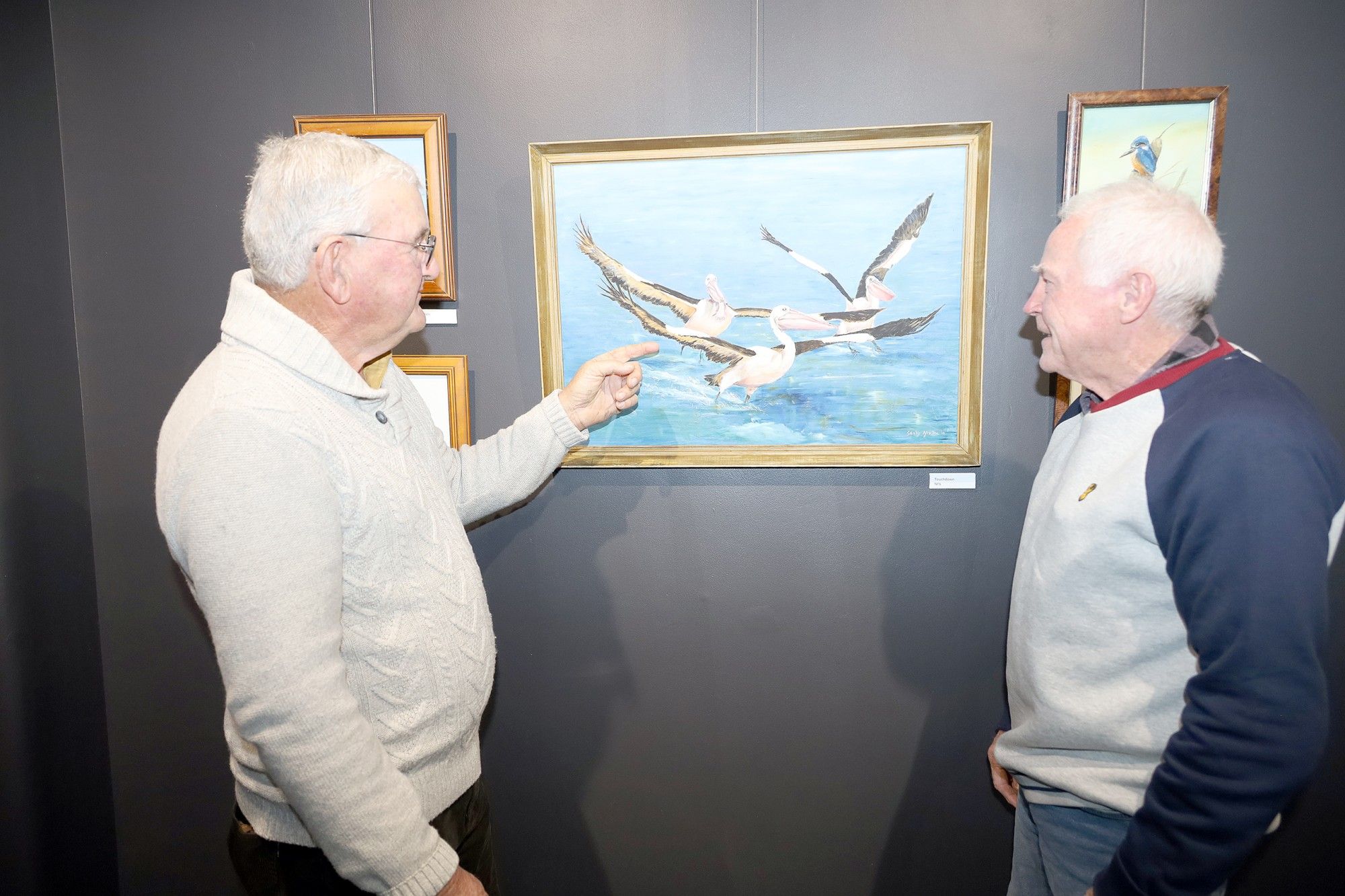 Col Gebert and Rod McLean discussing the details in one of over 50 paintings on display at the exhibition opening night.