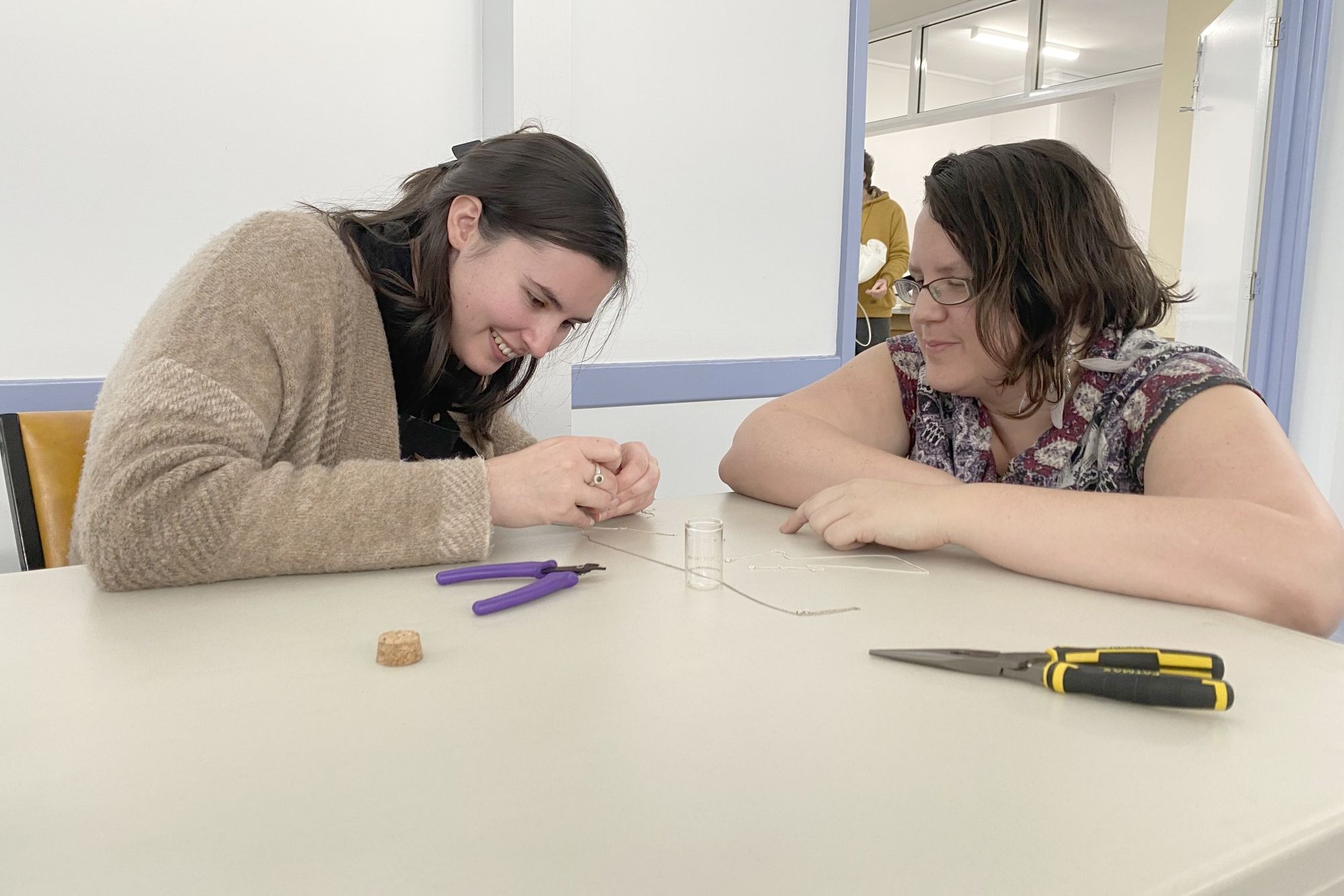 Kim Adams helps Emily Kirton mend a broken necklace at the Repair Cafe.