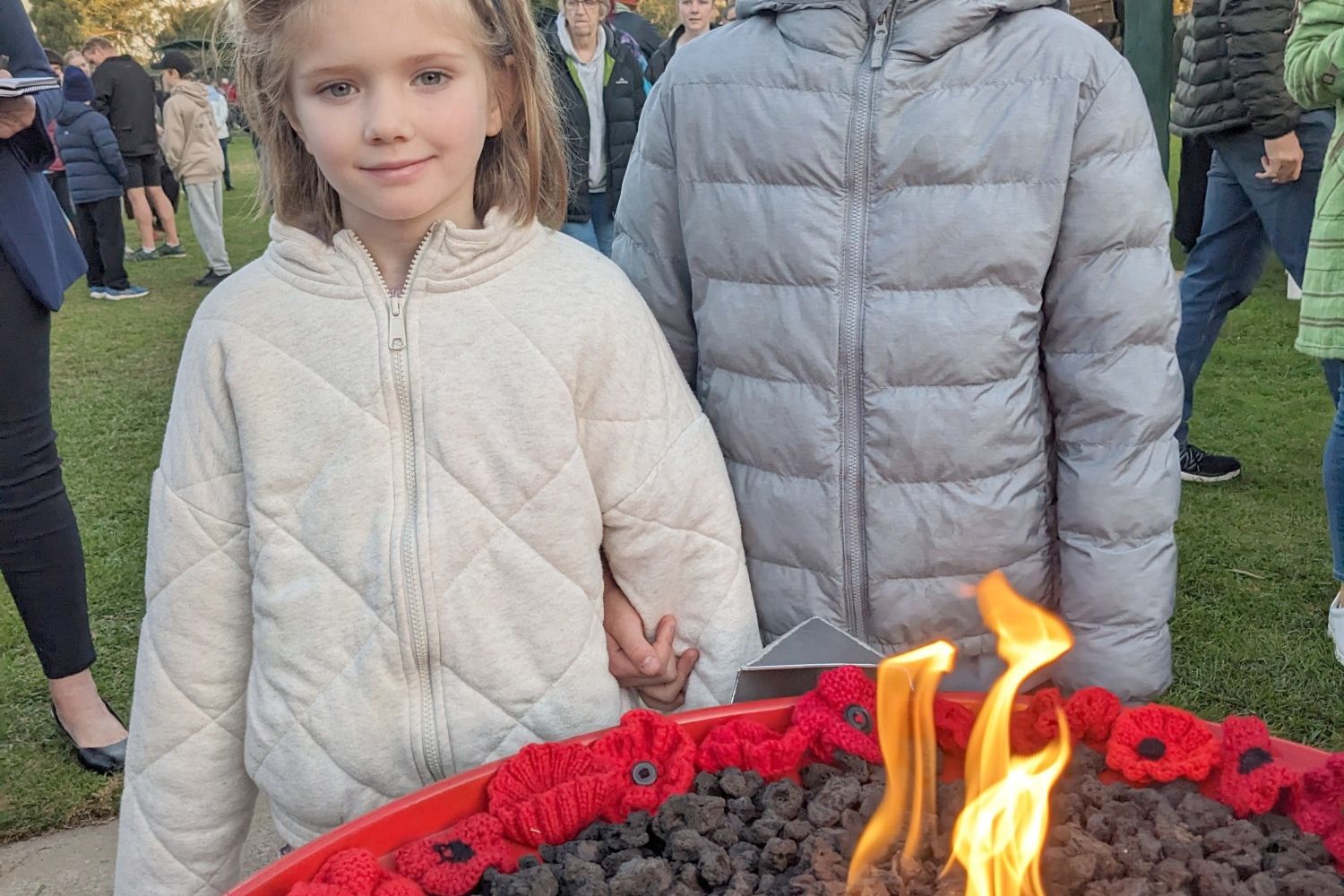Horsham youngsters Esme and Violet Holmes beside a poppy-framed flame at the dawn service. The girls later placed a poppy on the Cenotaph wall that carries the name of their great-grandfather Arch McIntyre, who served in New Guinea during the Second World War.
