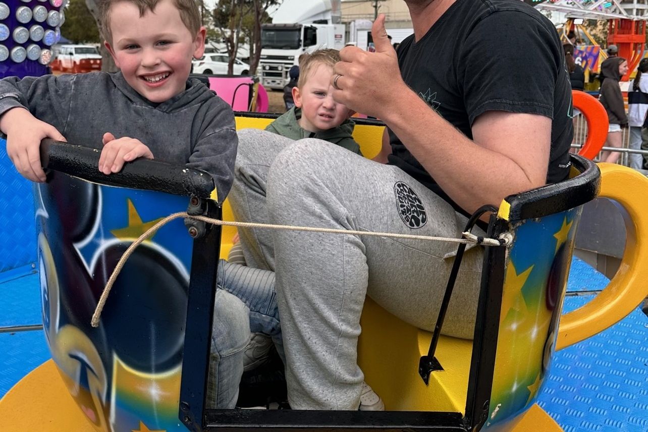 Max (left), Eddie and dad Marcus Lang take a spin on the teacups in between Thursday's eruption of showers and hail at the 2023 Warracknabeal Show. Showgoers were not deterred by the chilly, wet conditions, and there were a great number of entries and exhibits for patrons to explore. Credit MEL JEFFERIES