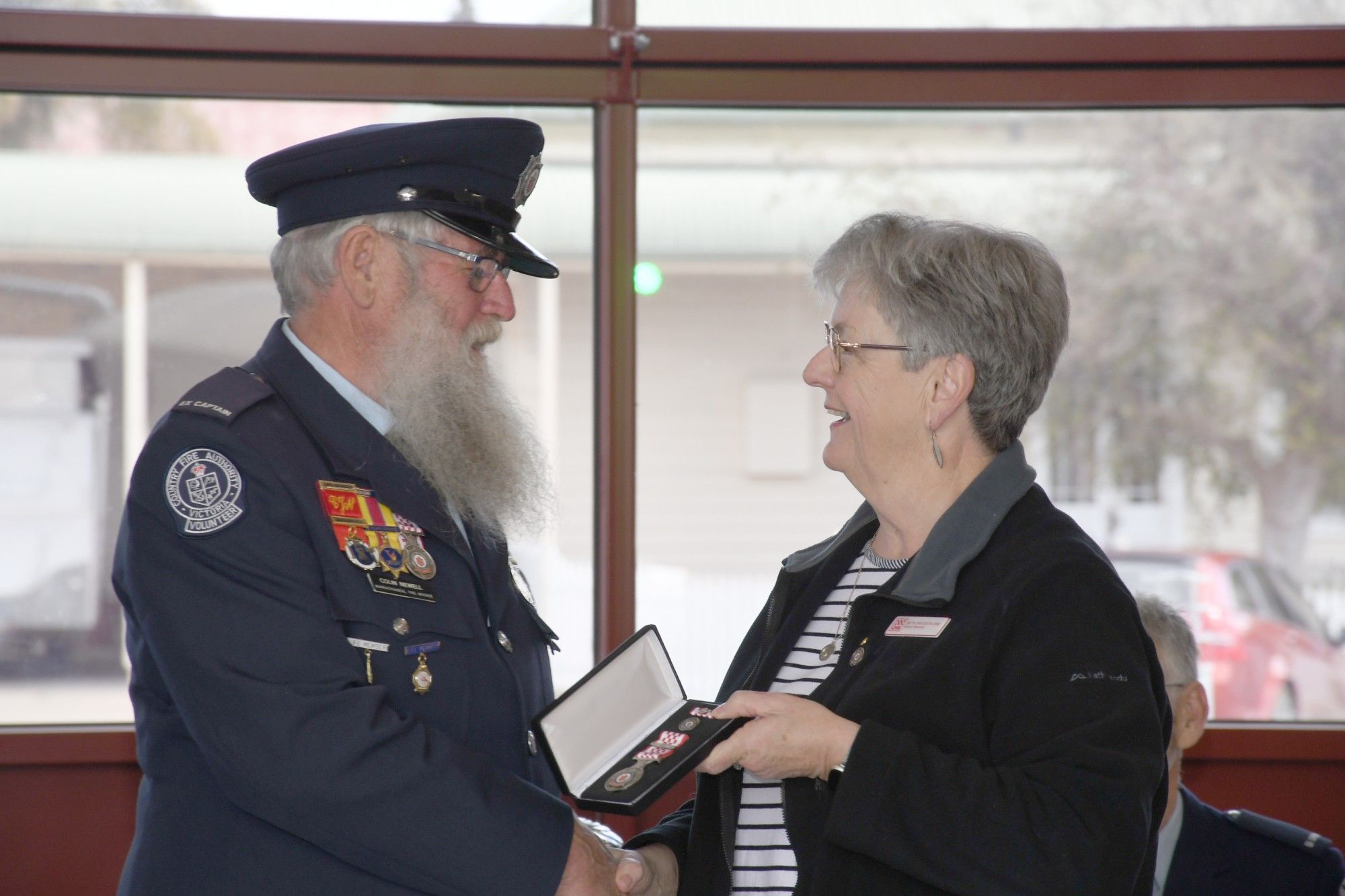 Colin Newell receives his 55-year service badge from CFA board member Beth Davidson.