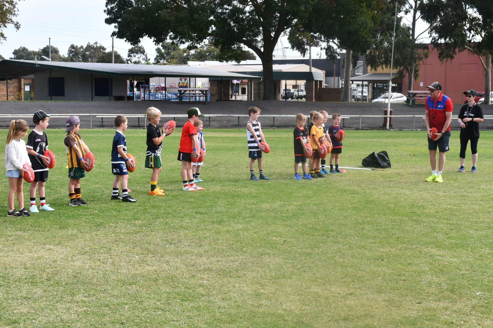 AFL Wimmera Mallee participation coordinator David Kennedy teaching young kids how to kick the ball.