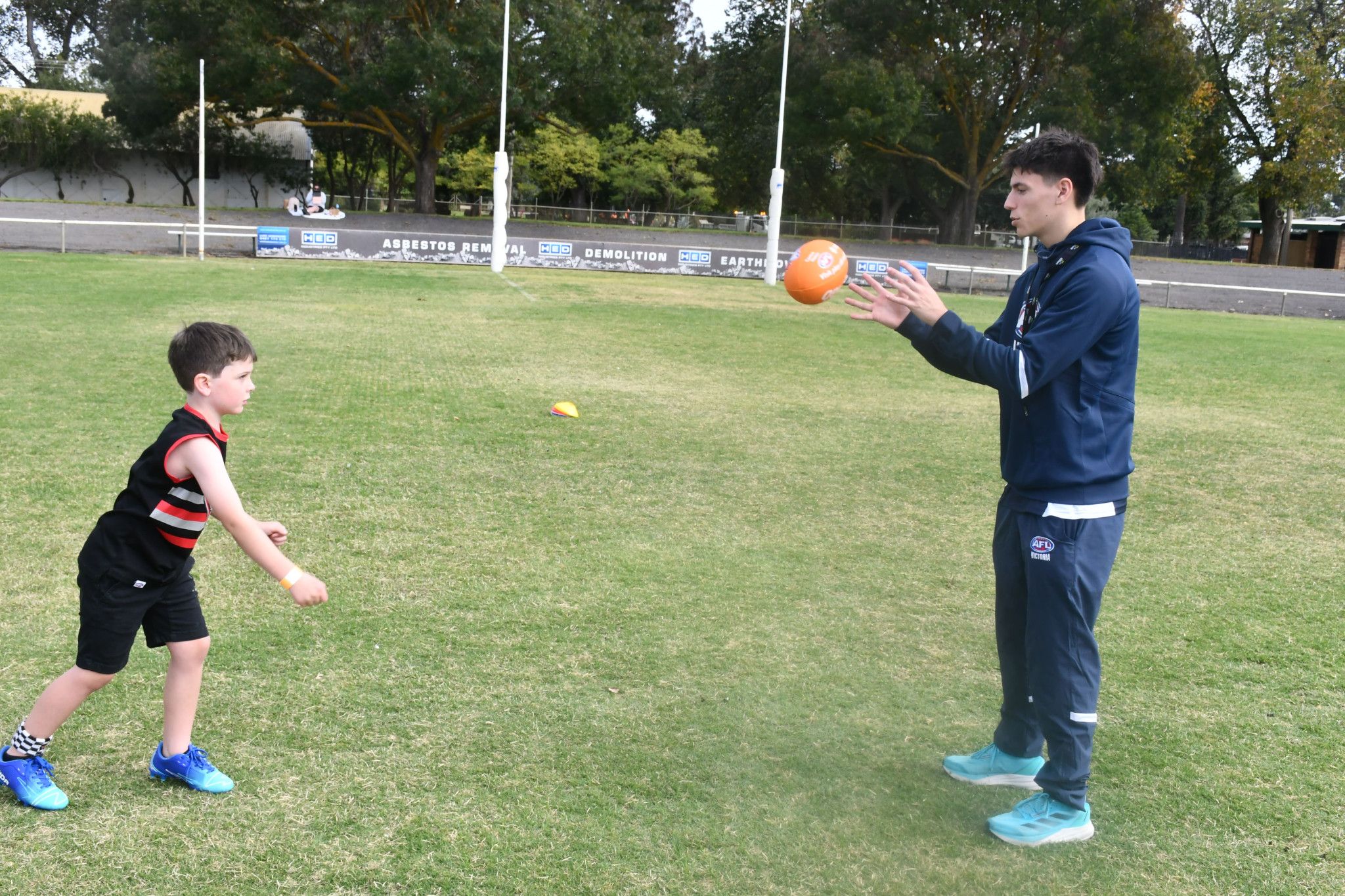 Oaka, 6, of Dimboola, passing the ball to the AFL Victoria game development officer Harry Robinson.