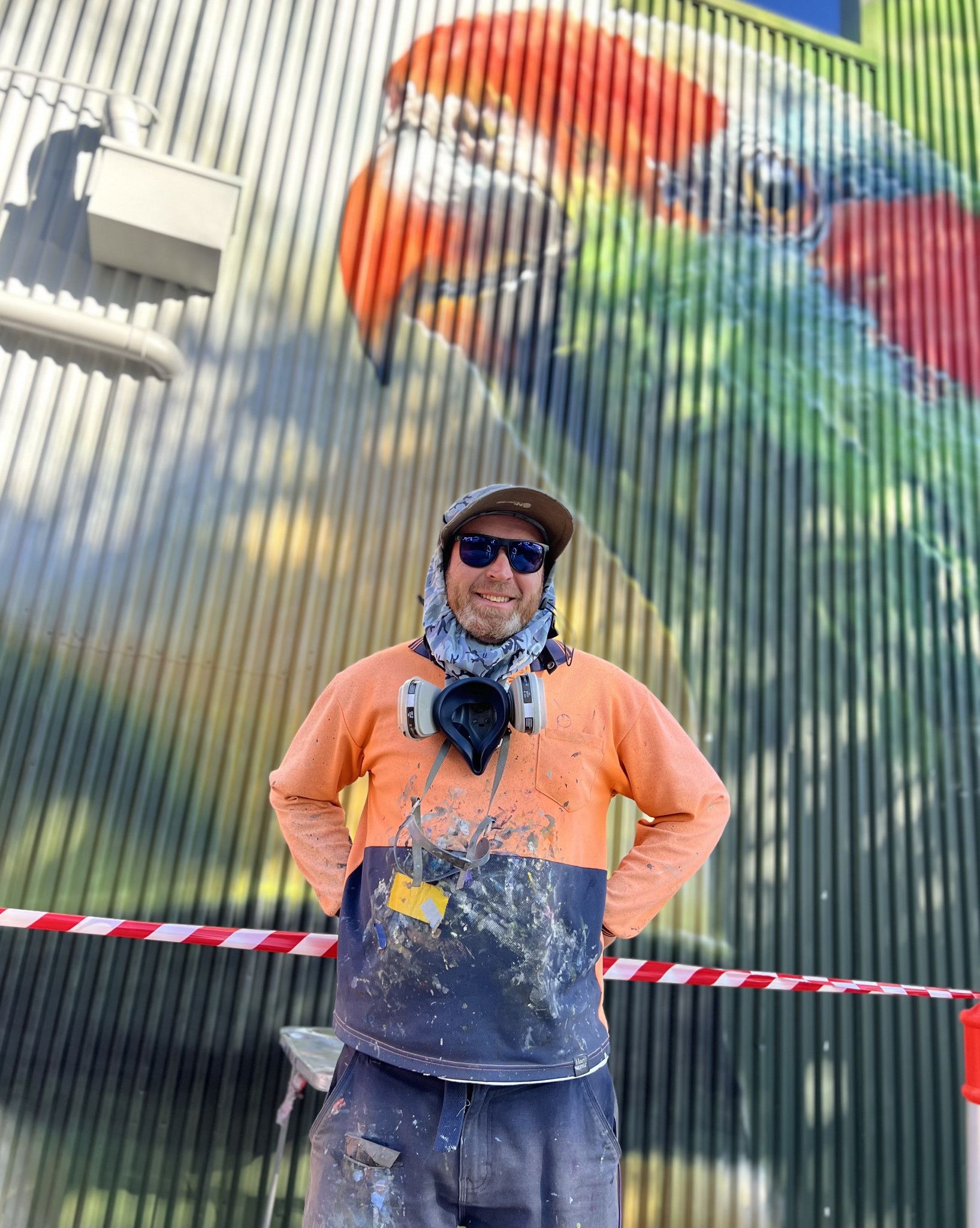 Artist Jimmy Dvate stands in front of his mural of a musk lorikeet on the back wall of the Horsham newsagency. The mural blends art and nature in a vibrant tribute to local wildlife.