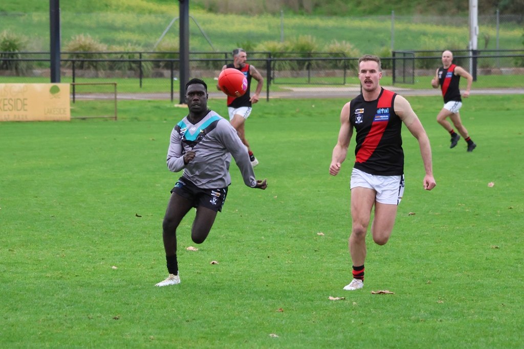 Swifts' Justin Puruntatameri and Noradjuha Quantong's Zach Kelly run for the loose ball during their round 12 senior football clash. The Bombers prevailed 14.12 (96) to 7.6 (48).