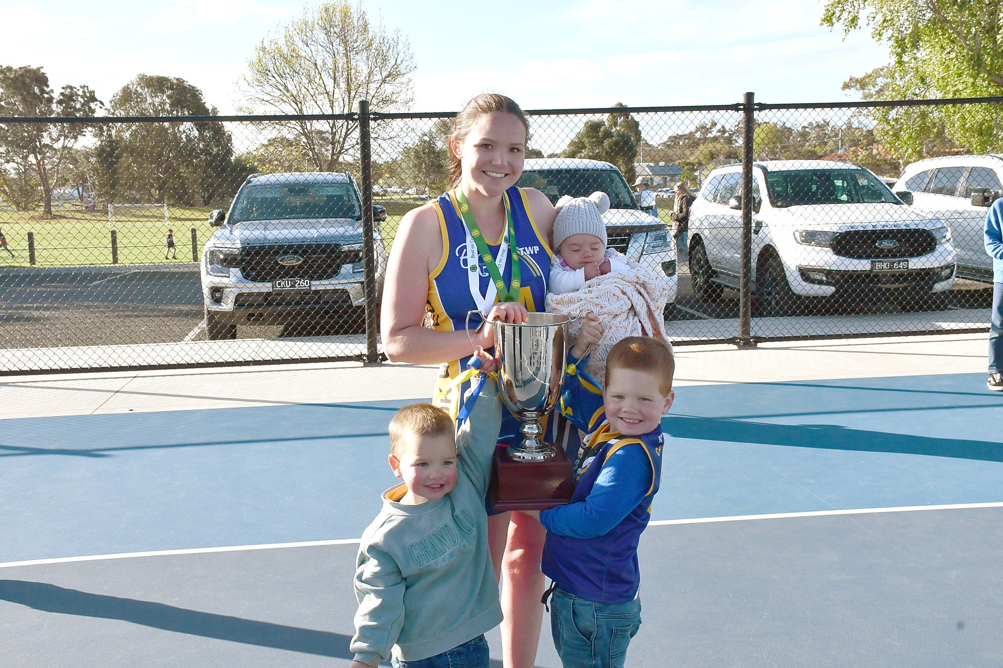 Courtney Cameron holding the premiership cup with her three children. Jasper, Poppy and Xavier.