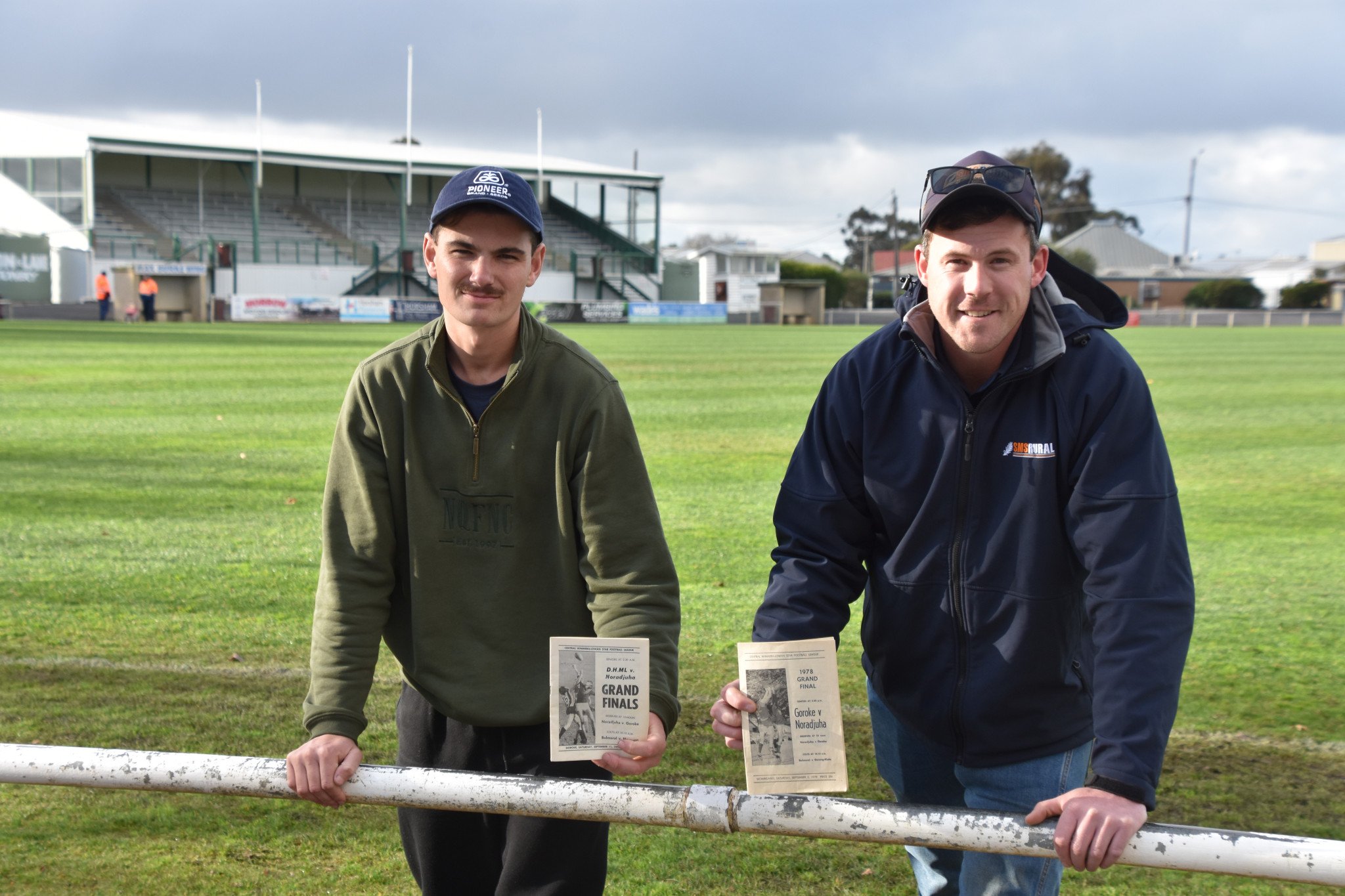 Noradjuha Quantong president Austin Smith, together with Ben Scott (left), whose family have represented the club over multiple generations. The pair are holding programs from the Central Wimmera grand finals during the 1970s- part of numerous items of memorabilia that will be on display.