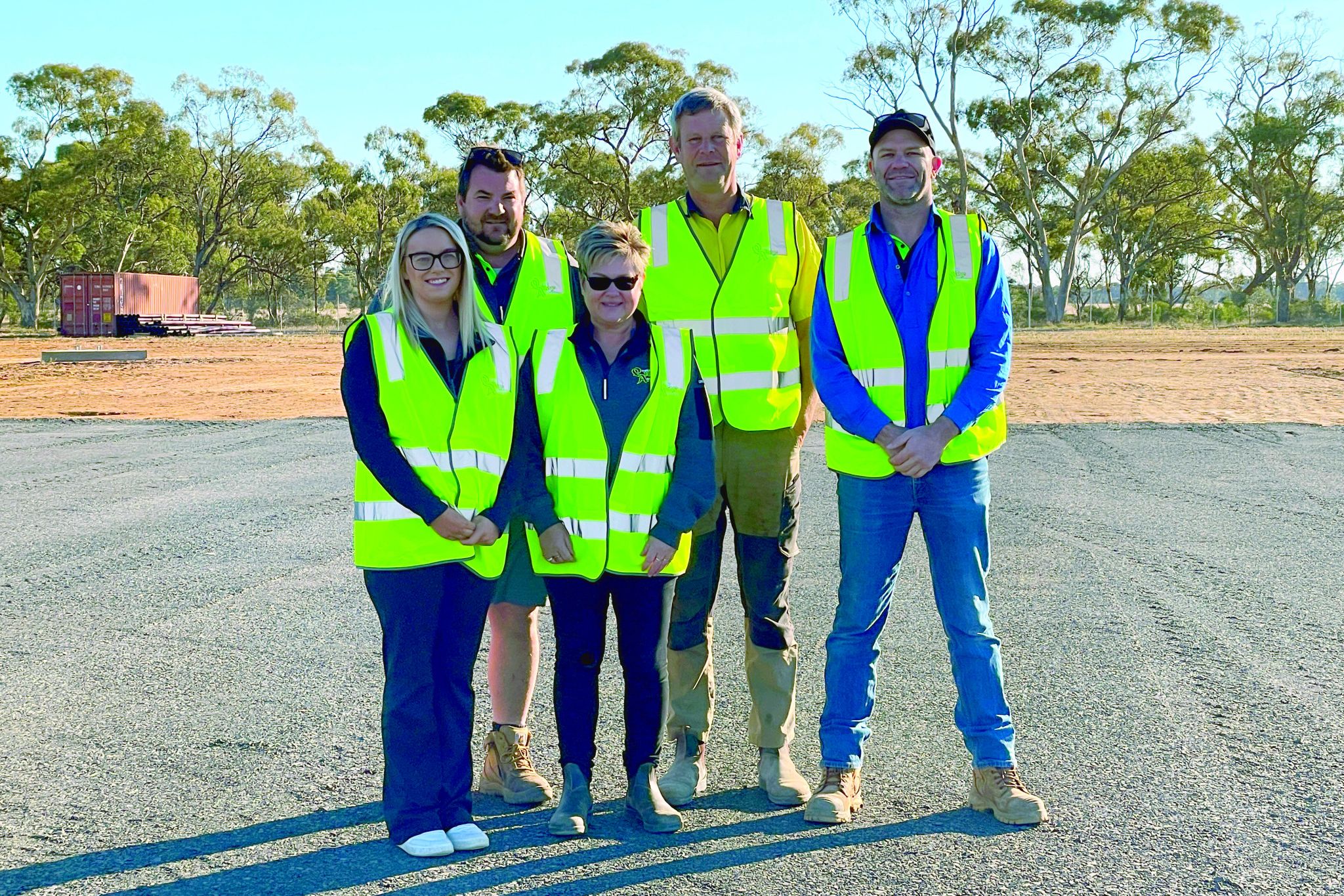 Rebecca Winsall, Scott Somers, Donna Ey, Paul Johns and Micha Mueller on the grounds of their hay plant as the first base layer is laid.