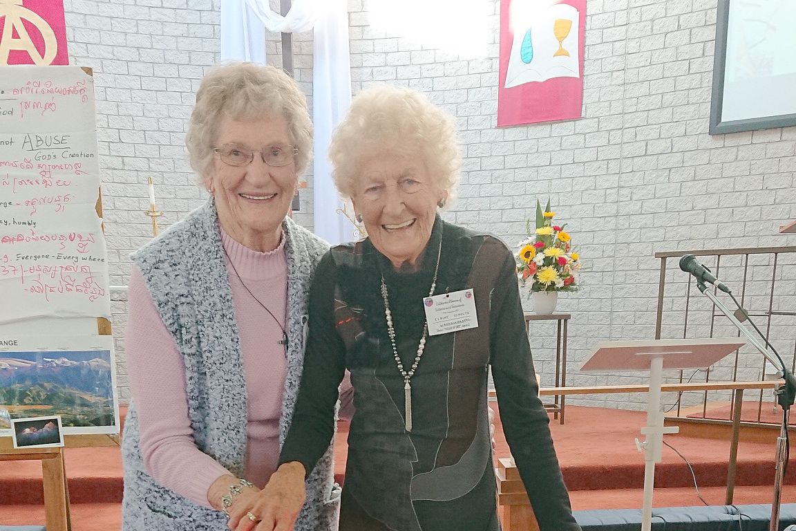 Elaine Schultz cutting the 100th birthday cake with Ruth Shaw.