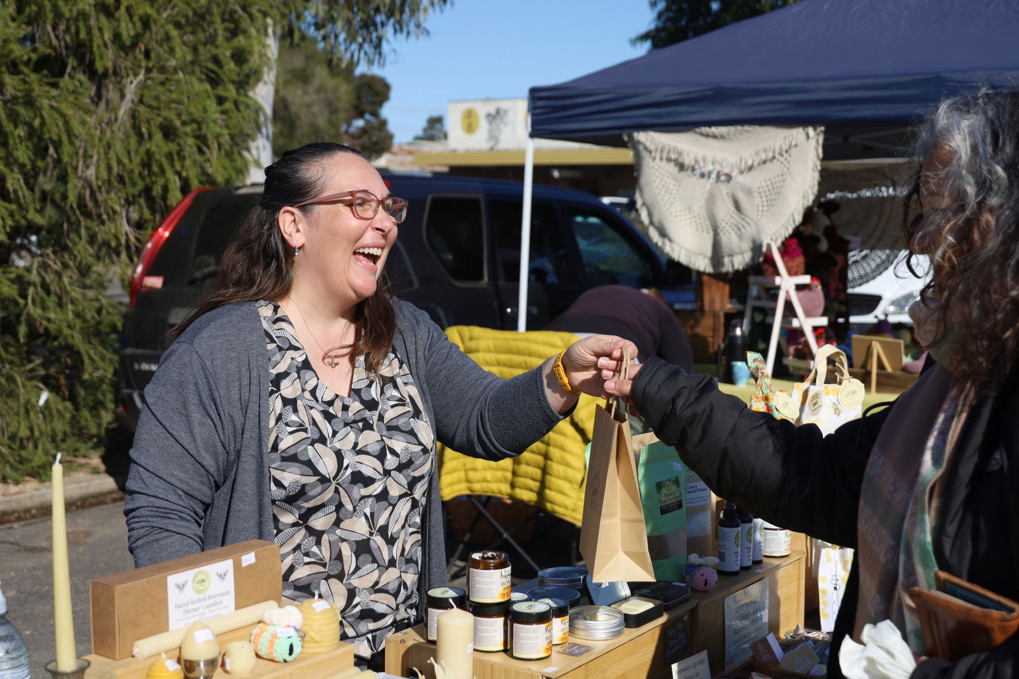 Kate Morgan serves a customer at her Narrow Road Living stall. Photo credit: Les Graetze