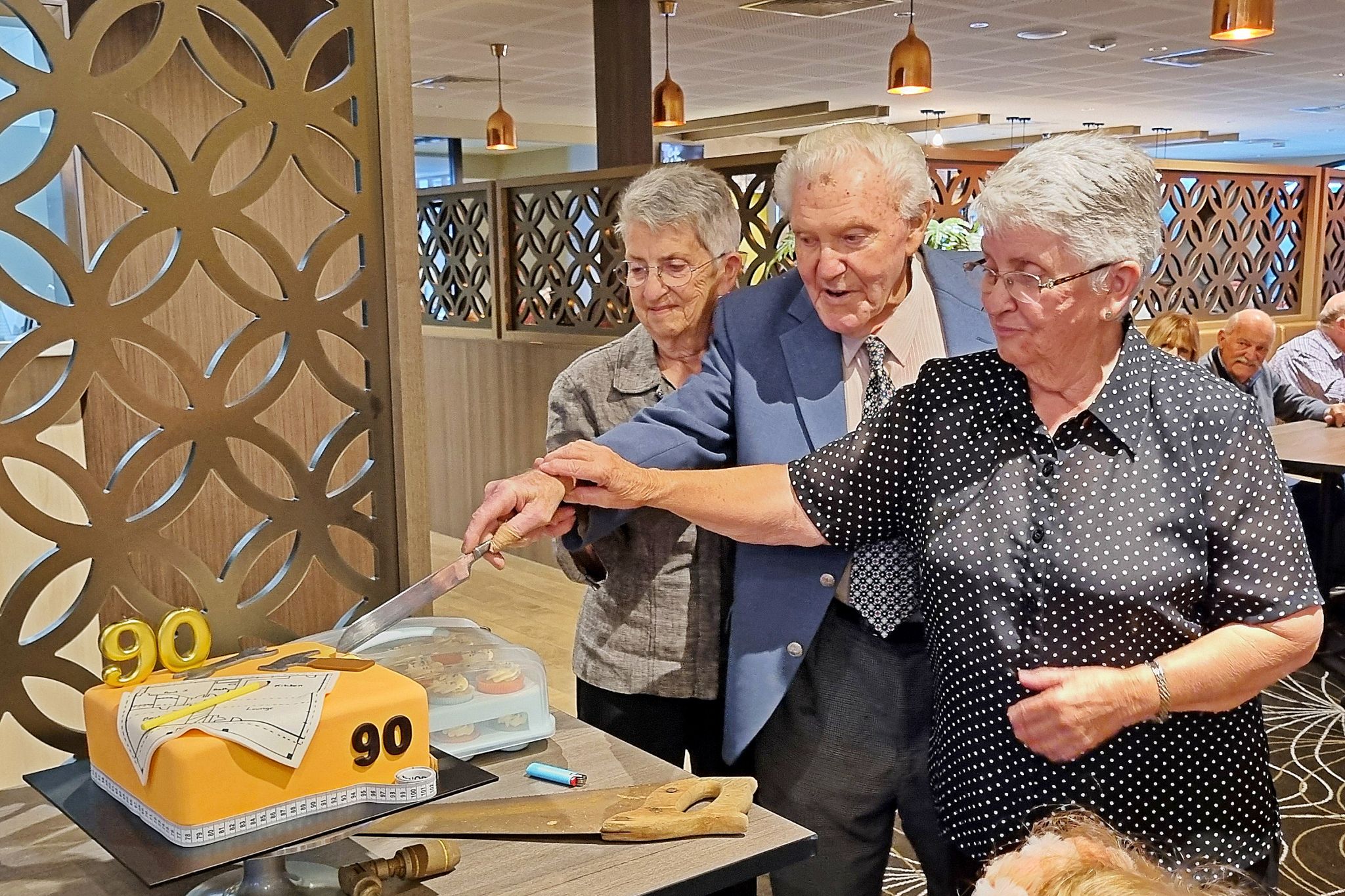 Ian Ballinger cutting his 90th birthday cake with family on March 23.